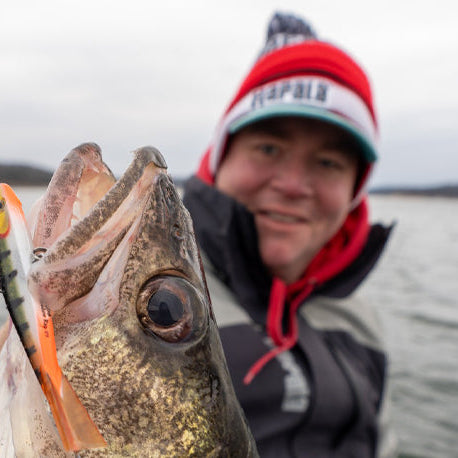 Man holding a Walleye up to the camera on a big lake